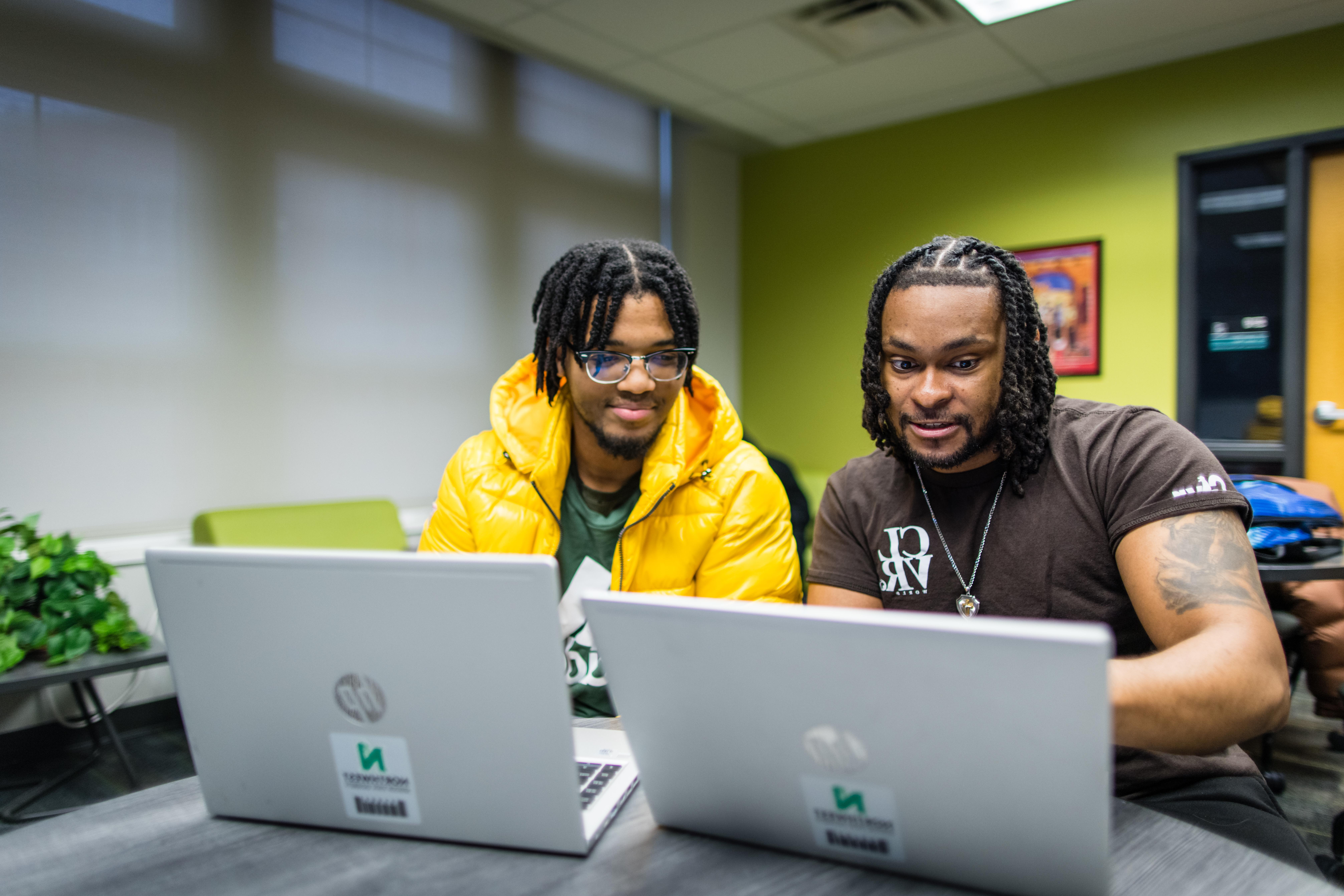 一对学生使用他们的西北笔记本电脑在多元化和包容性办公室内合作.