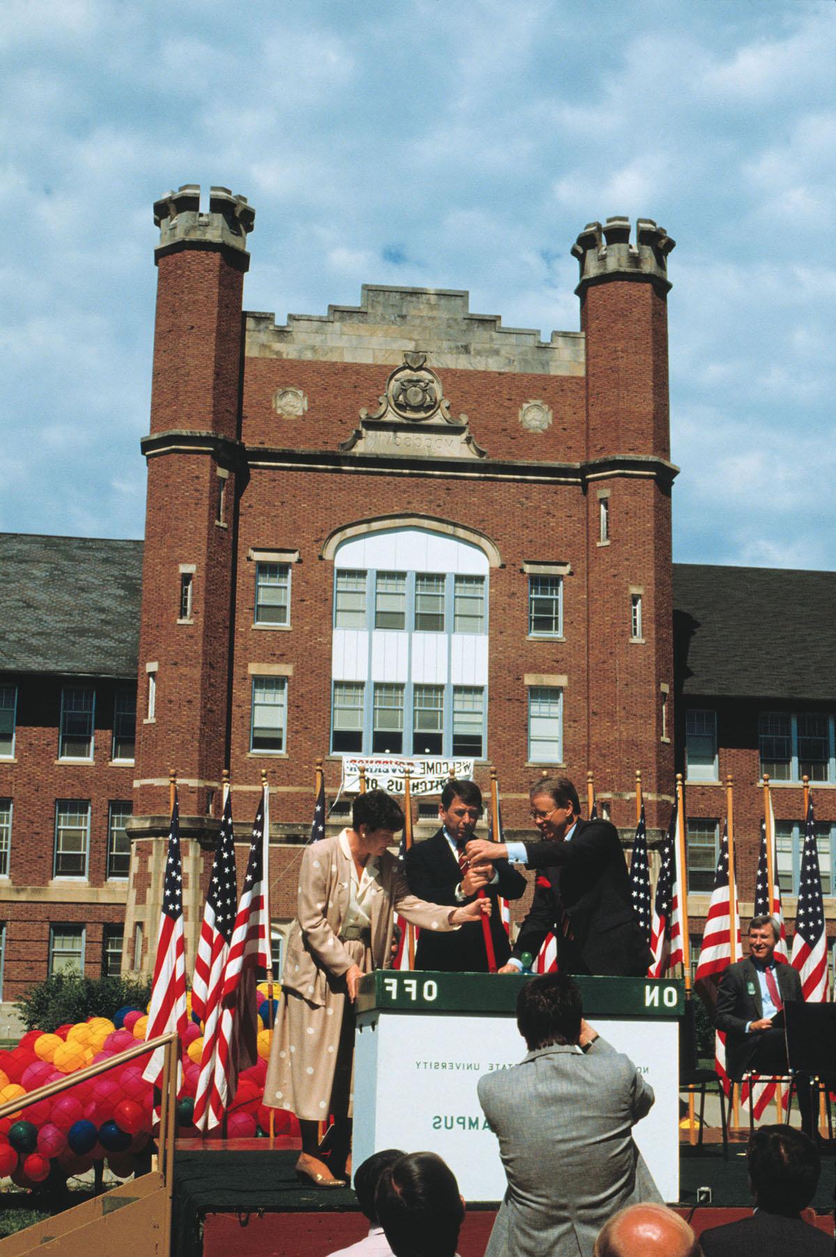 和记棋牌娱乐校长迪恩·哈伯德(左)拉开仪式的开关, “电子校园”于八月六日正式启用. 1987年8月18日，与州长. 约翰·阿什克罗夫特和密苏里州高等教育专员谢拉·艾瑞. 和记棋牌娱乐是全国第一所拥有校园计算机系统的公立大学.