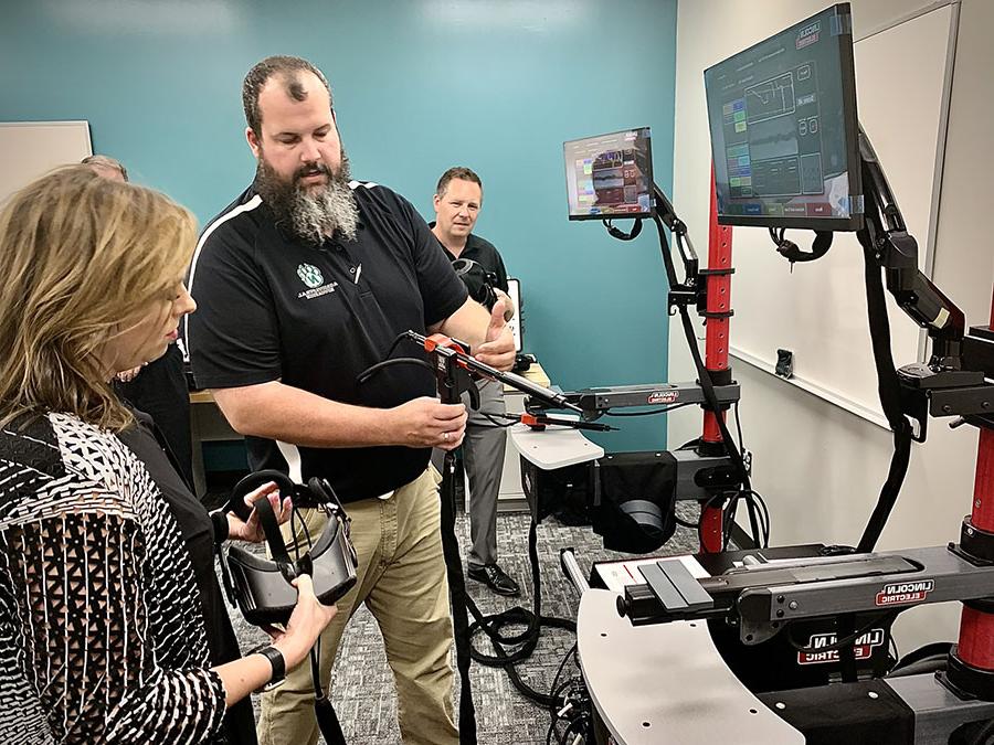 Matthew Bax, an agricultural sciences instructor at Northwest, demonstrates how to use a welding simulator in the remodeled McKemy Center with Shad Burner, director of federal initiatives with the Missouri Dept. of Economic Development, and Michelle Hataway, acting director of the Missouri Dept. of Economic Development. 